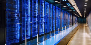A modern data center with rows of illuminated blue server racks lining a sleek corridor, representing the advanced technology powering AI development.