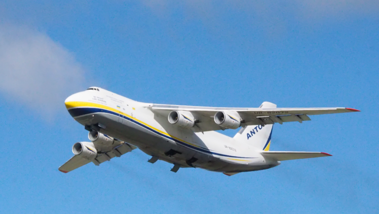 A large Antonov AN-124 cargo plane with Ukrainian markings takes off against a clear blue sky, symbolizing resilience and hope during wartime.
