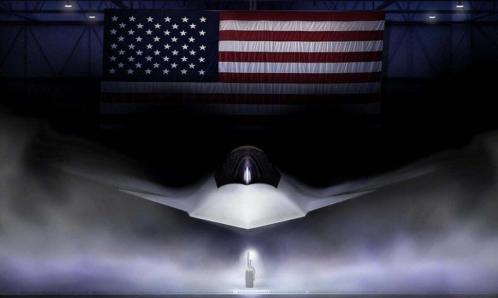 A dark hangar with a large American flag hanging overhead, illuminating a stealthy, angular aircraft shrouded in mist, with a spotlight highlighting its nose and a small figure standing below.