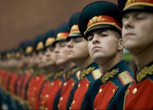 A line of Russian soldiers in red and green uniforms with gold accents, standing in formation during a military parade.