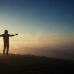 A serene figure stands at a crossroads under a dramatic sky, releasing glowing chains into the wind, symbolizing forgiveness and detachment for personal growth.